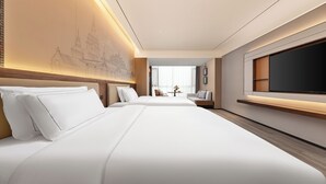 Een hotelkamer met twee bedden, een grote flatscreen televisie, een bureau met stoel en een wandplank.