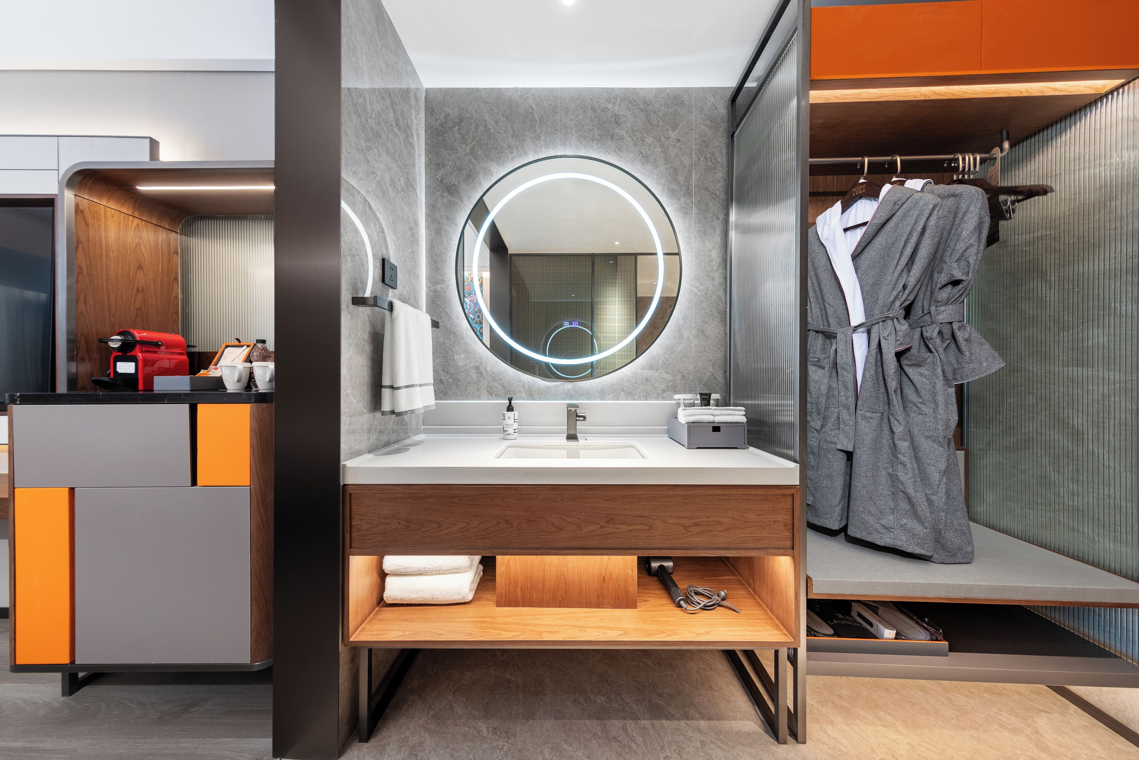 A modern bathroom with a round mirror, a sink, and a robe hanging on a rack.