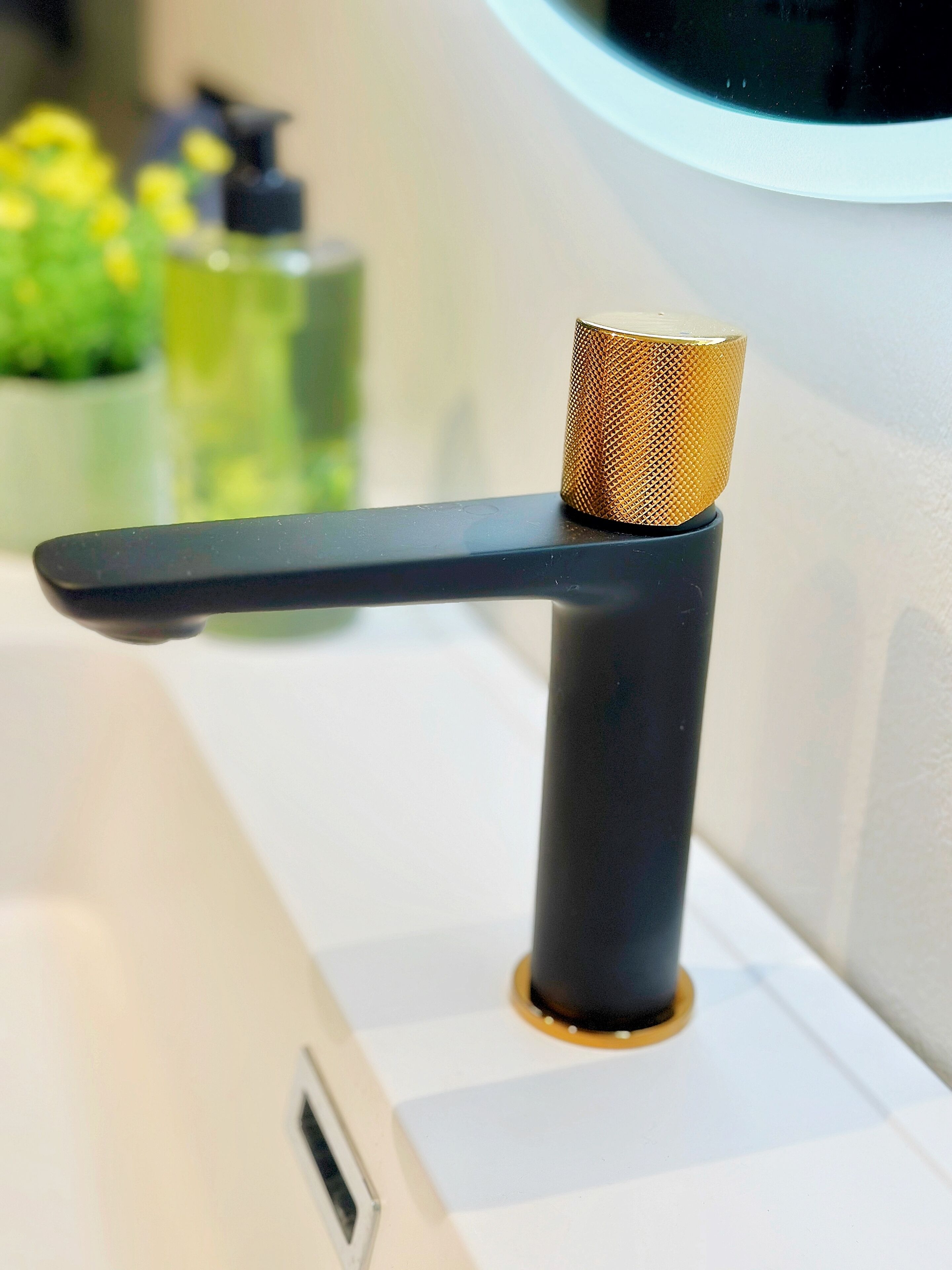 A bathroom sink with a black faucet and a gold-colored faucet knob.