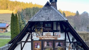 A traditional half-timbered building with a steeply pitched roof, a chimney, and a sign indicating it is the largest cuckoo clock in the world.