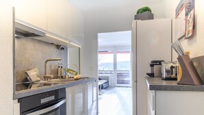 A modern kitchen with a built-in oven, a coffee machine, and a small herb garden on the refrigerator.
