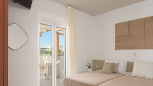 Une chambre à coucher comprenant un lit, un téléviseur, une porte-fenêtre coulissante donnant sur un balcon et un grand tableau abstrait accroché au mur.