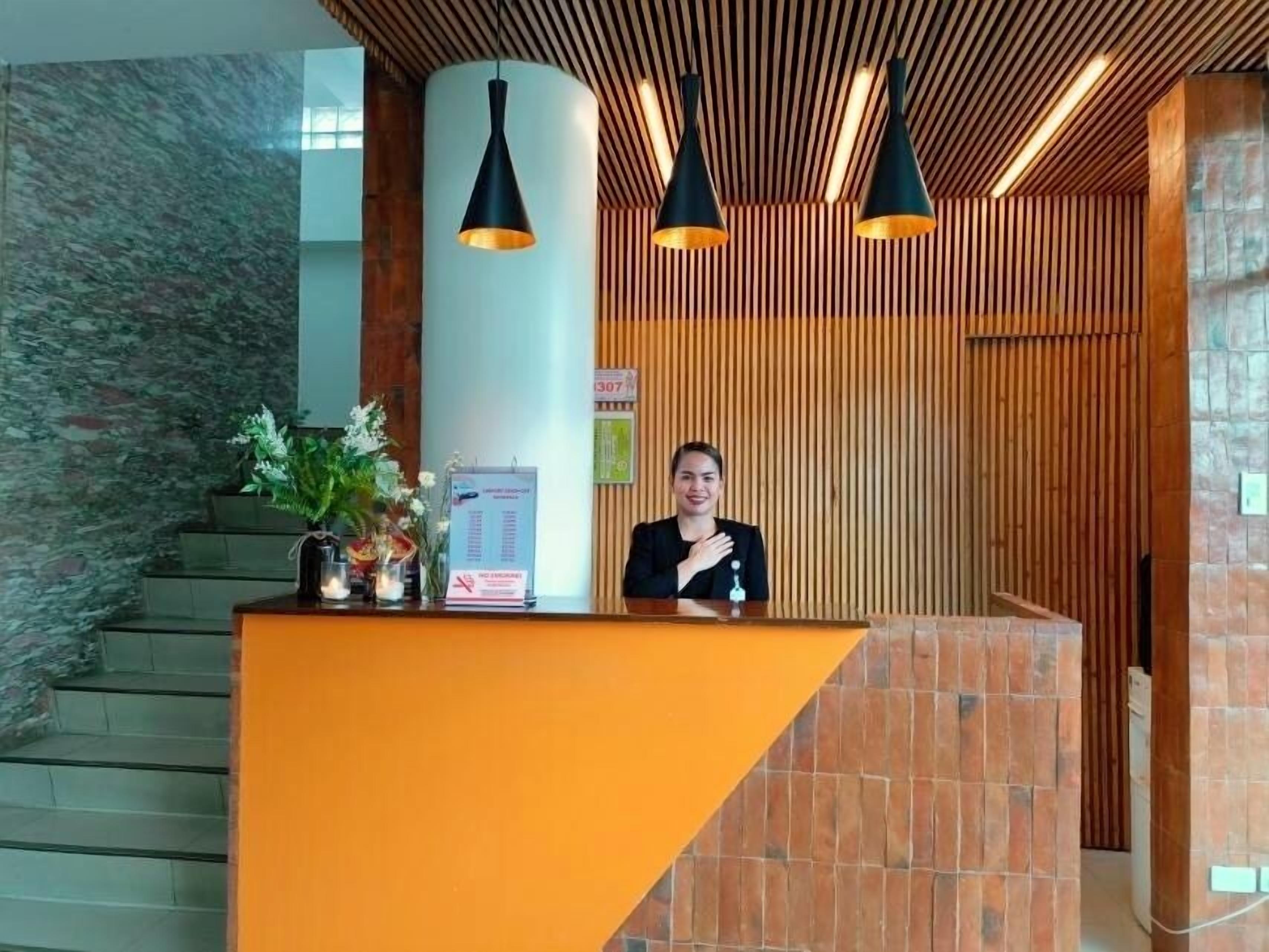 A reception desk with a modern design, featuring a wooden panel wall and a stone-textured backdrop.