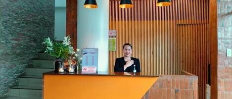 A reception desk with a modern design, featuring a wooden panel wall and a stone-textured backdrop.