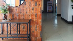 Un hall d’entrée avec un banc en bois, un miroir rond et un mur recouvert de carreaux.