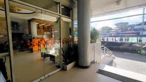Un bâtiment moderne avec une entrée en verre, un escalier menant à un niveau supérieur et une vue sur la rue.