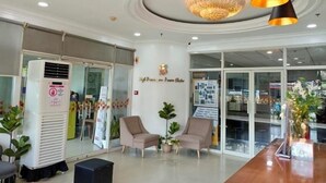 Un espace d’accueil comprenant un climatiseur blanc, deux chaises, un comptoir d’accueil en bois et un lustre.
