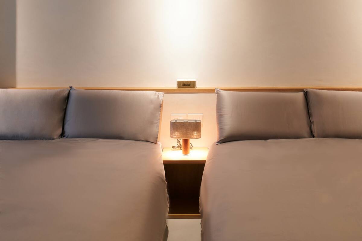 A hotel room with a bed, a nightstand, and a lamp.