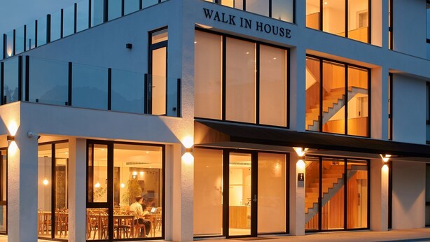 Un edificio moderno con un letrero que dice "Walk in House" y una escalera que conduce a un nivel superior.