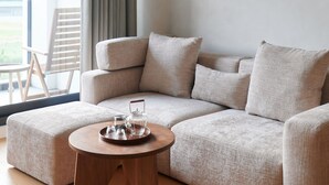 Una sala de estar moderna con un sofá modular, una mesa de centro redonda de madera y un cuadro en la pared.