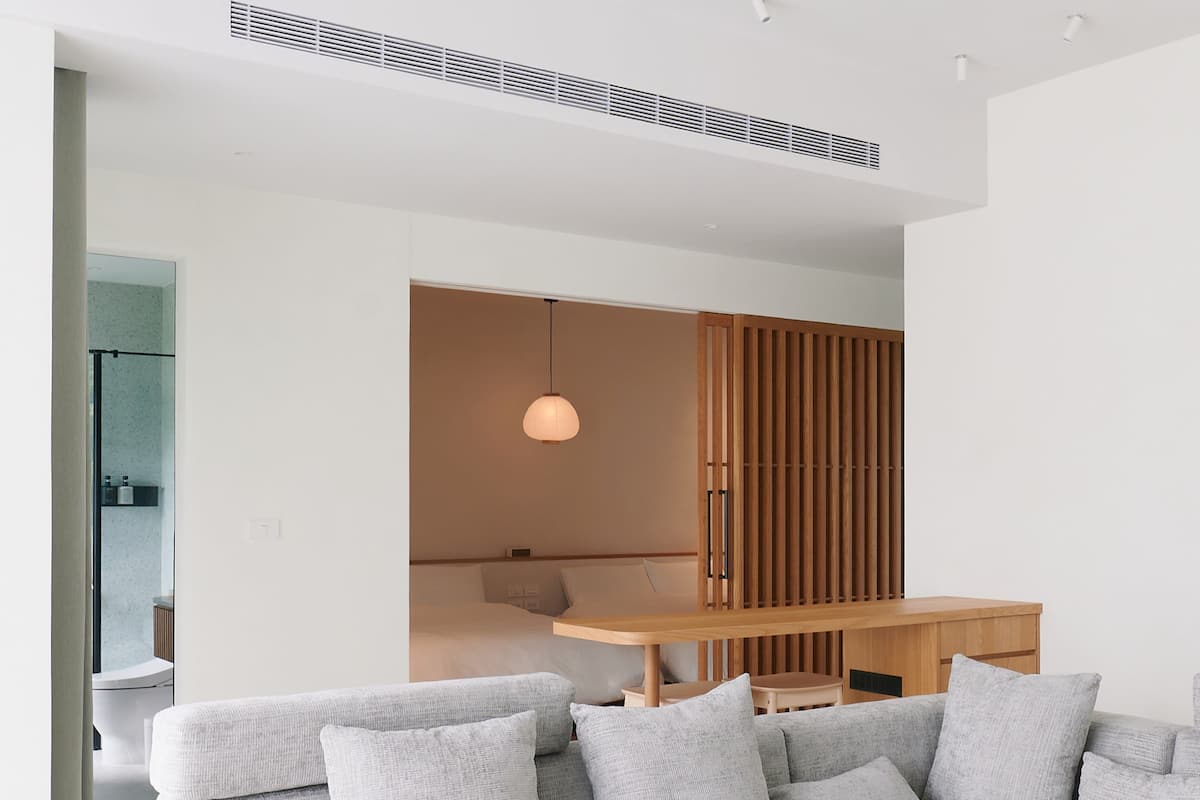A modern living room with a grey sectional sofa, a wooden coffee table, and a remote control on it.