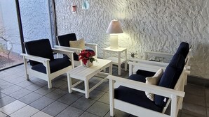 A modern living room with a sloped ceiling, white textured walls, and a mix of black and beige tiled flooring.