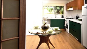 A kitchen with green cabinets, a glass-top table, and a view of the outdoors. - Beautiful lakeside unit, walk to train station, schools and Eastland (Ringwood East)