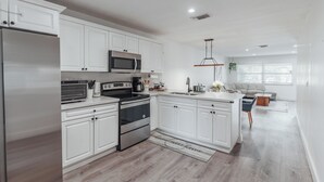 Una cocina moderna con armarios blancos, electrodomésticos de acero inoxidable y una isla central.