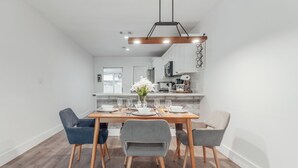 Un comedor moderno con una mesa de madera dispuesta para cuatro personas, rodeada de sillas tapizadas en gris.