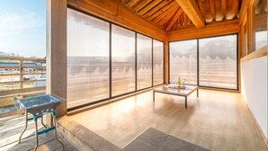 A spacious balcony with a grill, a table with a bottle and glasses, and large windows offering a view of the surrounding area. - Gyeongju Aratteul Hanok Pet Pension (Gyeongju)