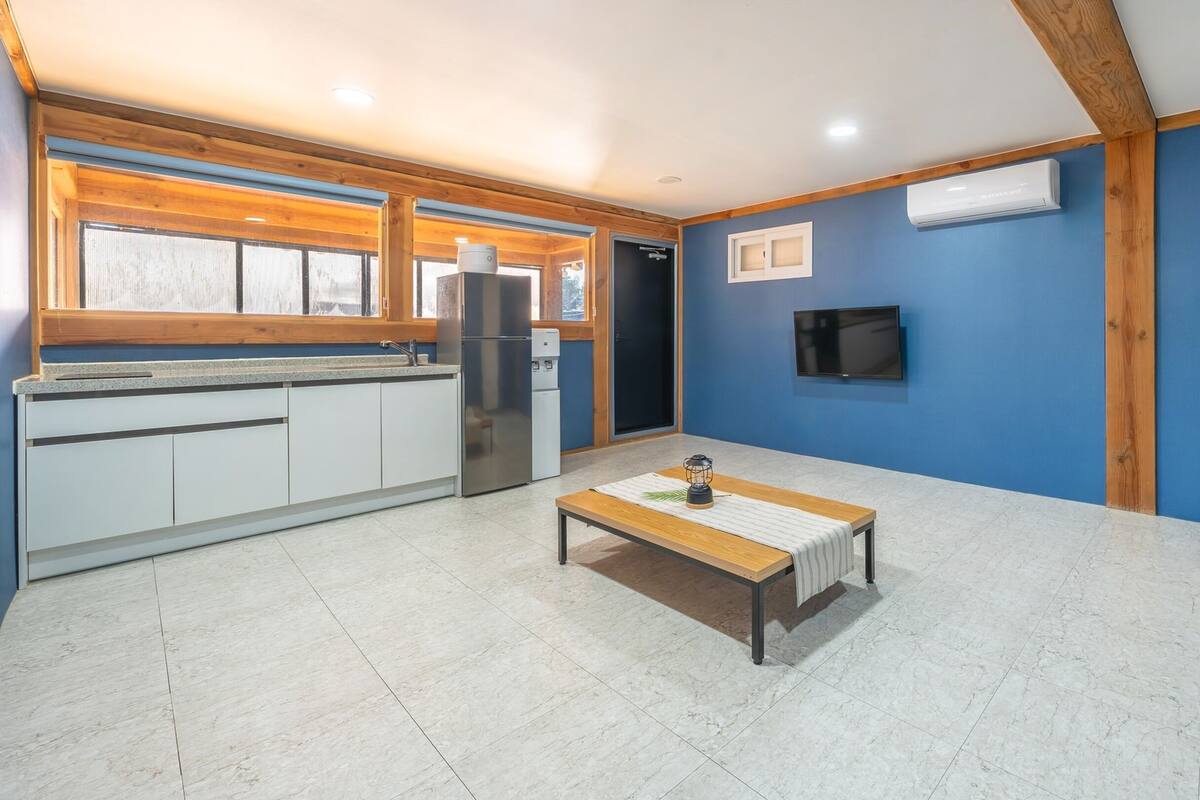 Eine moderne Küche mit weißen Schränken, einem Edelstahlkühlschrank und einem Holztisch mit einer Laterne.