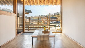 A room with a wooden table, a bottle of wine, and glasses, with a view of traditional buildings outside. - Gyeongju Aratteul Hanok Pet Pension (Gyeongju)