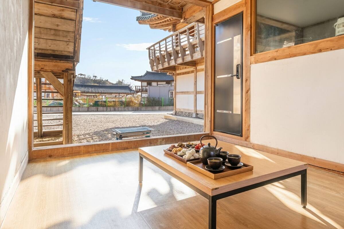 Ein traditioneller japanischer Raum mit Tatami-Böden, einem niedrigen Holztisch mit Teeservice und Blick auf ein traditionelles Gebäude draußen.