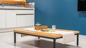 A kitchen with white cabinets, a wooden table with a green basket and a glass, and a blue wall. - Gyeongju Aratteul Hanok Pet Pension (Gyeongju)