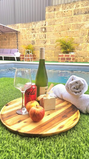 A wooden tray with a bottle of wine, a glass, a Coca-Cola can, a wrapped gift, an apple, and a towel by a poolside. - Joyful Living 
A private space all to yourself, complete with a beautiful pool 
 (Beeliar)