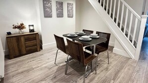 A dining area with a table set for six, a wooden cabinet, and a staircase.