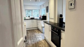 A modern kitchen with white cabinetry, a black countertop, and a built-in oven.