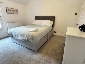 Ein Schlafzimmer mit einem Bett, einem Heizkörper, einem weißen Schrank und einem Wandbild.