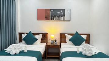 A hotel room with two wooden beds, teal bedding, and a nightstand with a lamp.
