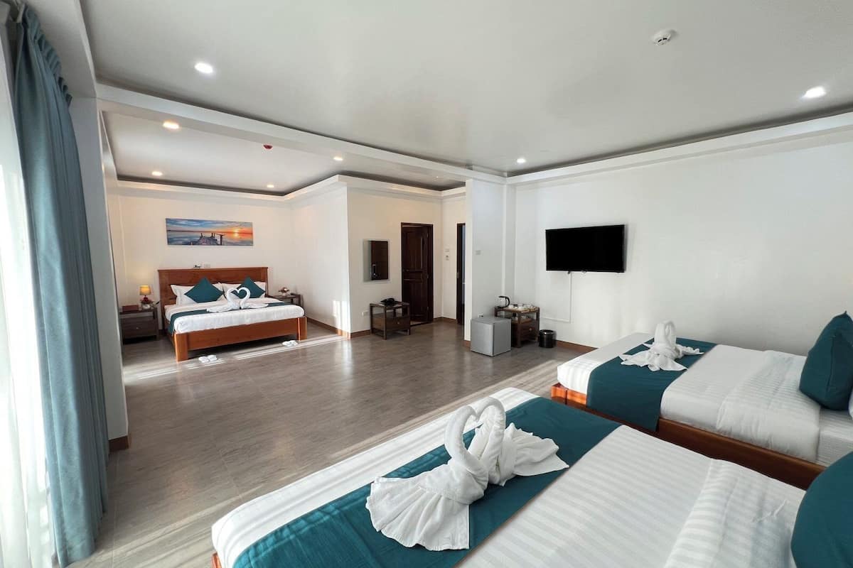 A hotel room with two beds, a TV, and a painting on the wall.
