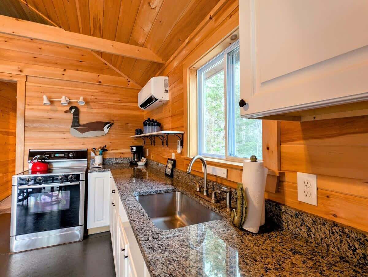 A modern kitchen with granite countertops, stainless steel appliances, and wooden paneling.