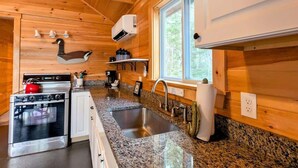 A modern kitchen with granite countertops, stainless steel appliances, and wooden paneling.