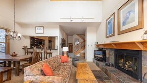 A spacious living room with a fireplace, a dining area, and a kitchen in the background. - Quicksilver 1664 (Keystone)