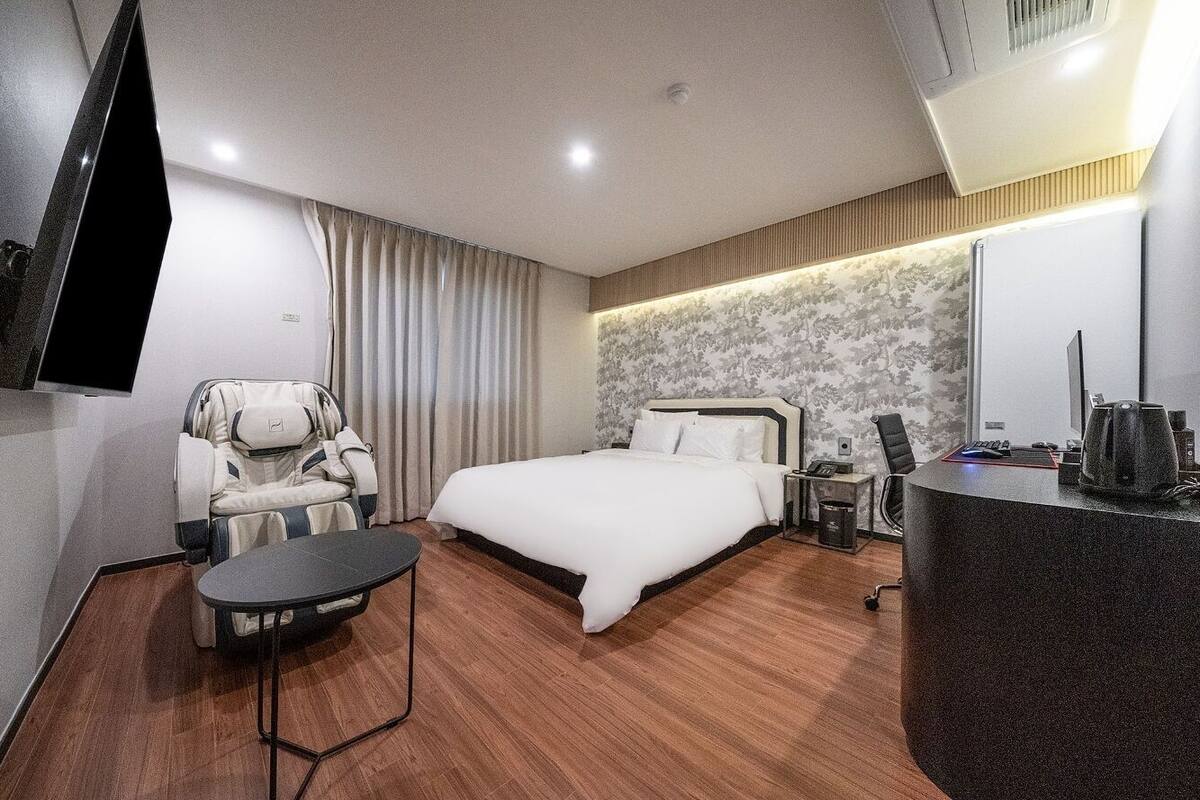Une chambre d’hôtel équipée d’un lit, d’un fauteuil massant, d’un bureau et d’une télévision.