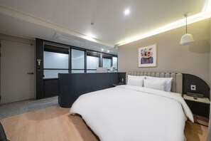 Ein modernes Hotelzimmer mit einem großen Bett, einem Schreibtisch und Blick auf die Stadt durch große Fenster.
