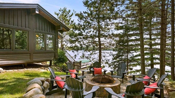 A wooden deck with Adirondack chairs and a stone fire pit.