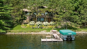A lakeside cabin with a dock, surrounded by dense forest.
