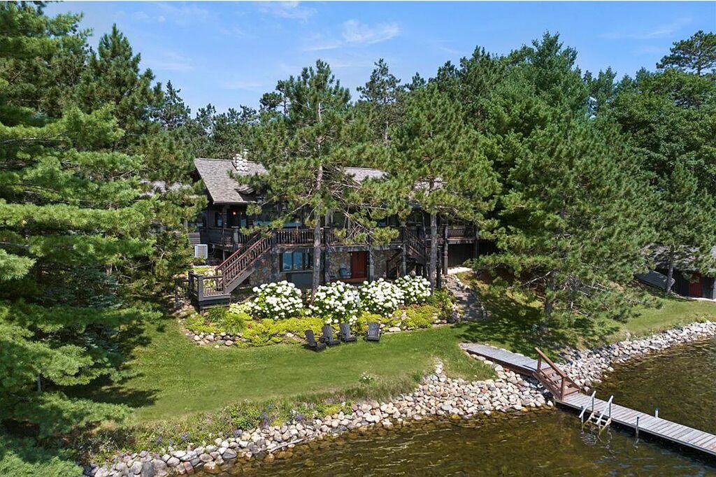 A lodge with a stone exterior, a wooden deck, and a pond.
