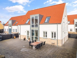 A residential building with a red-tiled roof, a patio with a table and chairs, and a visible garage. - 4 Star Holiday Home in Lokken (Lokken)
