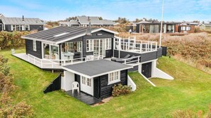A modern house with a deck, large windows, and a staircase leading to an upper level. - 5 Star Holiday Home in Lokken (Lokken)