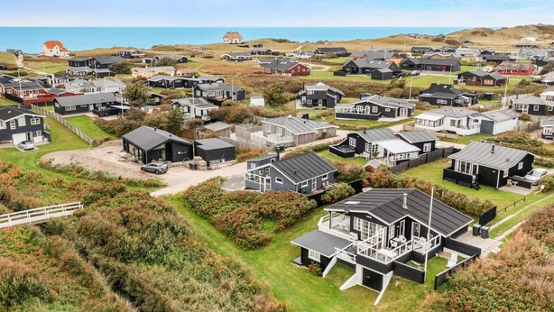 A coastal residential area with modern houses, a prominent house with a large deck, and a view of the sea. - 5 Star Holiday Home in Lokken (Lokken)