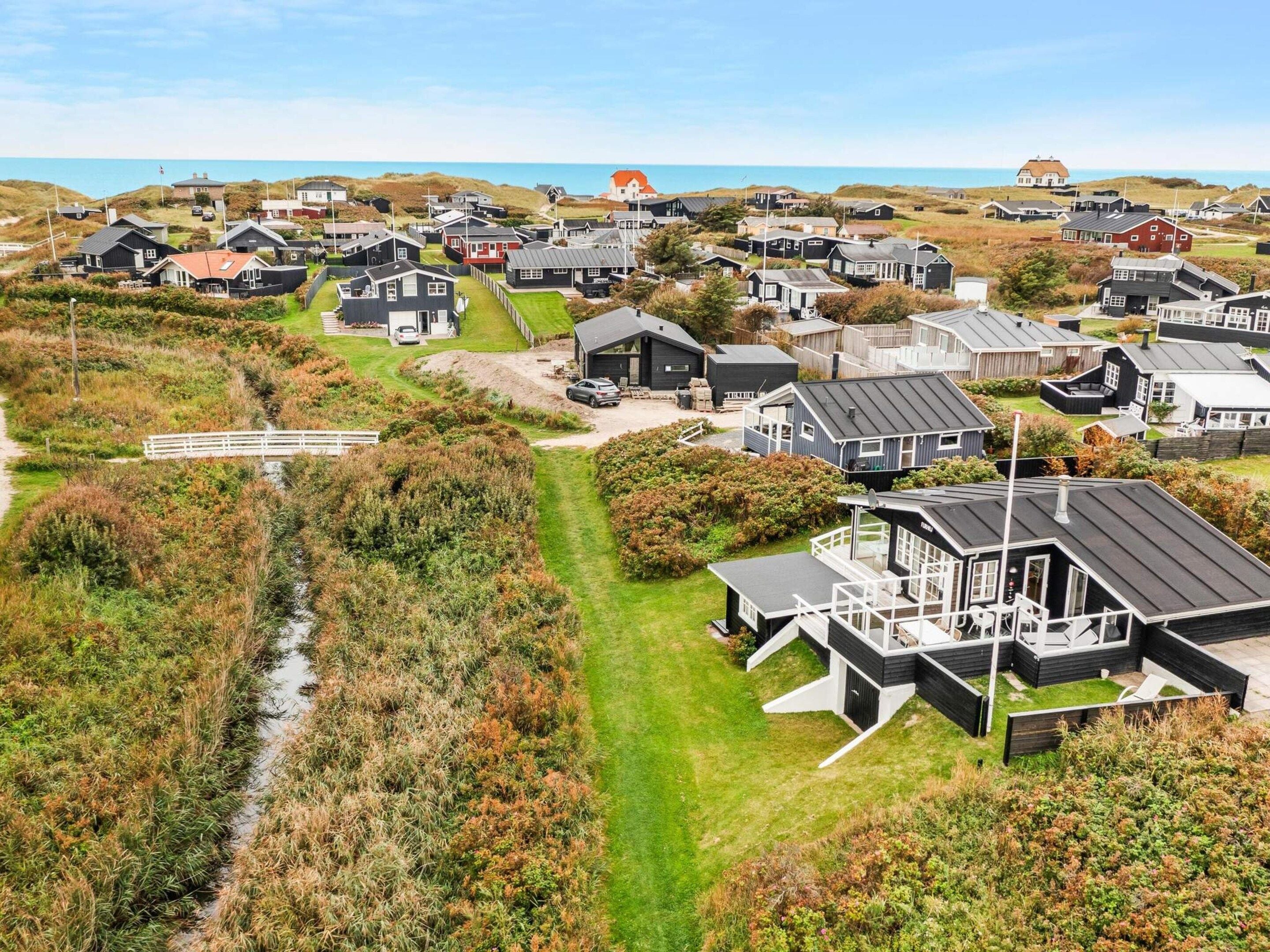 A coastal residential area with houses, a bridge, and a view of the sea.