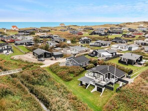 Un quartier résidentiel situé sur la côte, composé de plusieurs maisons, dont certaines sont dotées de garages attenants, et une maison remarquable avec une grande terrasse et un espace extérieur aménagé pour se détendre.