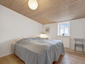 A bedroom with a bed, a window, a radiator, and a chair. - 5 Star Holiday Home in Lokken (Lokken)