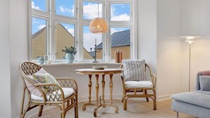 A room with a bay window, wicker chairs, a small round table, and a floor lamp. - 5 Star Holiday Home in Lokken (Lokken)