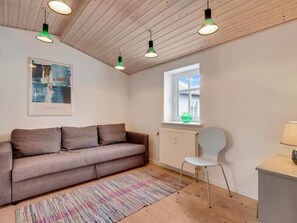 A modern living room with a sofa, a chair, a colorful rug, and a window with a view. - 5 Star Holiday Home in Lokken (Lokken)