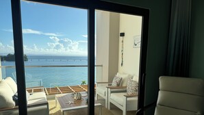 A modern living room with a large sliding glass door leading to a balcony overlooking a body of water and a bridge. - Rent a home away from home in front of the Best View of beautiful Samaná Bay! (Samana)