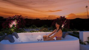 Una mujer sentada en un jacuzzi con vista al atardecer.
