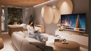 Una sala de estar moderna con un televisor de pantalla plana grande, un sofá, una mesa de centro y un comedor con una mesa de madera y sillas.