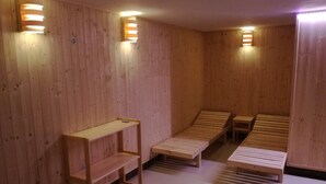 Ein Saunaraum mit Holzbänken und Regalen, sowie Wandleuchten.